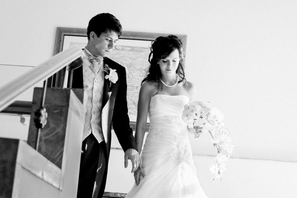 A Black and White candid moment of the groom and bride walking down the grand staircase captured as a fine art manifestation by Arnold Szmerling during an exclusive collaboration with the King David Jerusalem for the Visual Life Collection.
