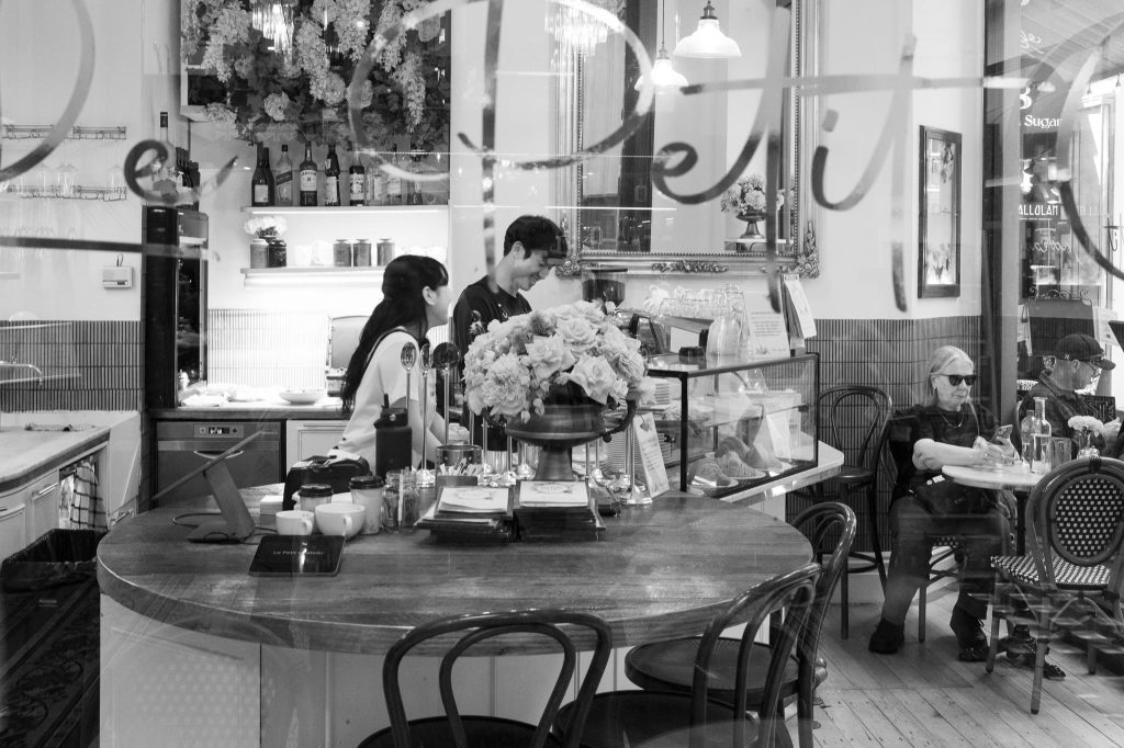 The laughing barristers preparing food in the Deli Block Arcade Melbourne, a work of passion by Arnold Szmerling captured in Black and White during his Leica Q3 street photography experience.