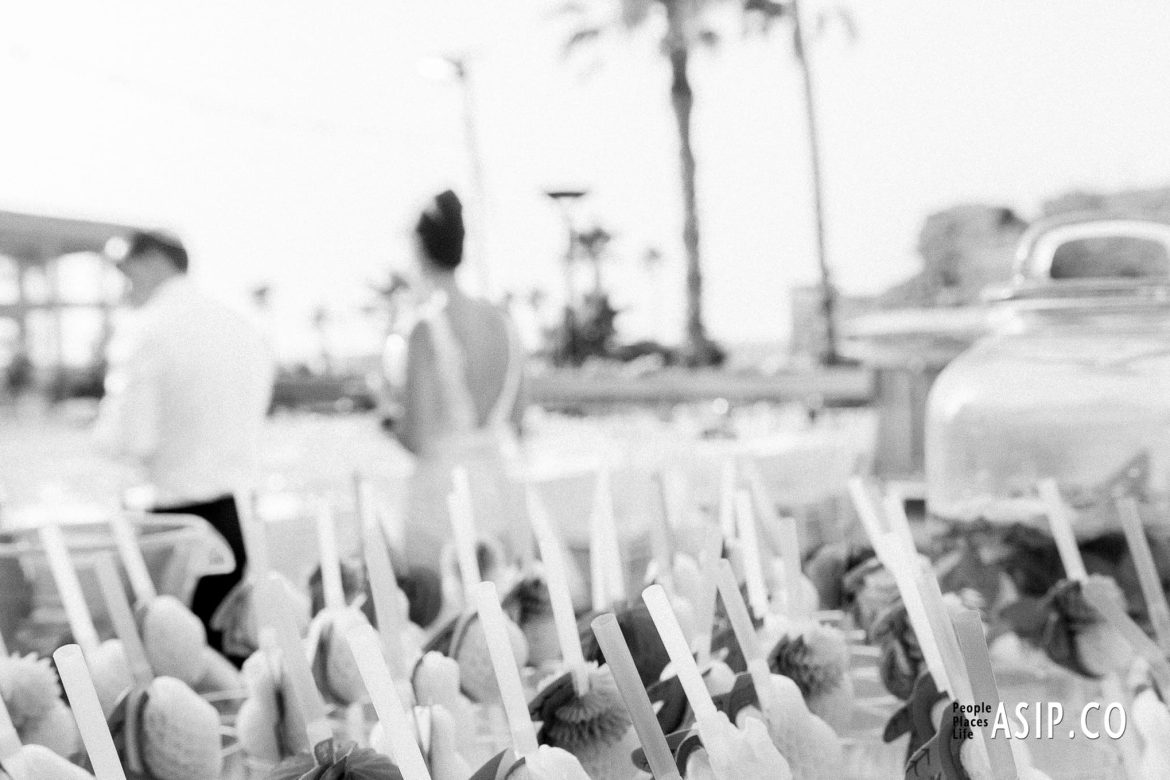 A stylish editorial of bride and groom at of focus in the background with finger food front of camera captured with a cinematic, analog-inspired aesthetic by Arnold Szmerling. This manifestation emphasizes the play of bokeh with grain and visual restraint of the Visual Life Collection.