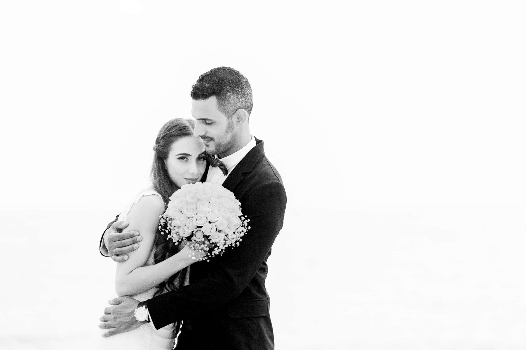 A curated editorial manifestation black and white candid of couple embracing at Tel Aviv beach, captured as a masterwork for the Visual Life Collection by Arnold Szmerling.