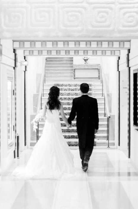 A rear view of the bride and groom walking down the foyer featuring the grand architecture captured as a fine art manifestation by Arnold Szmerling during an exclusive collaboration with the King David Jerusalem for the Visual Life Collection.